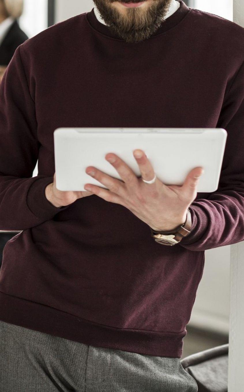 a man in a purple jumper looks at his tablet