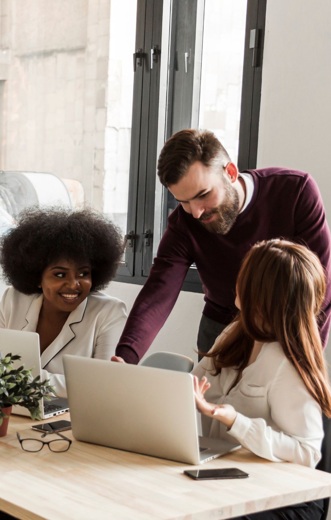 a friendly discussion takes place between a man looking over his female colleagues' computer