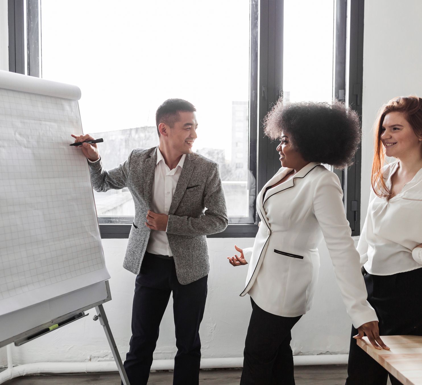 a man presents to his colleagues on a whiteboard